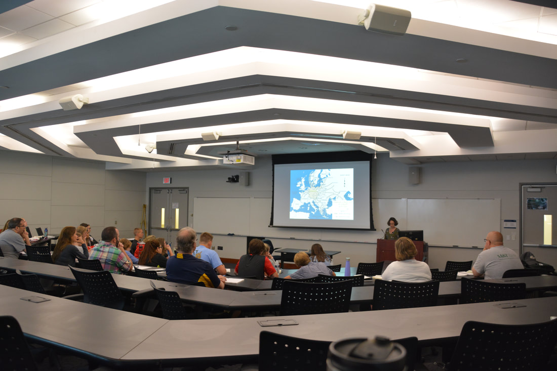 Wide angle view of a GW classroom with a professor lecturing in front of a whiteboard