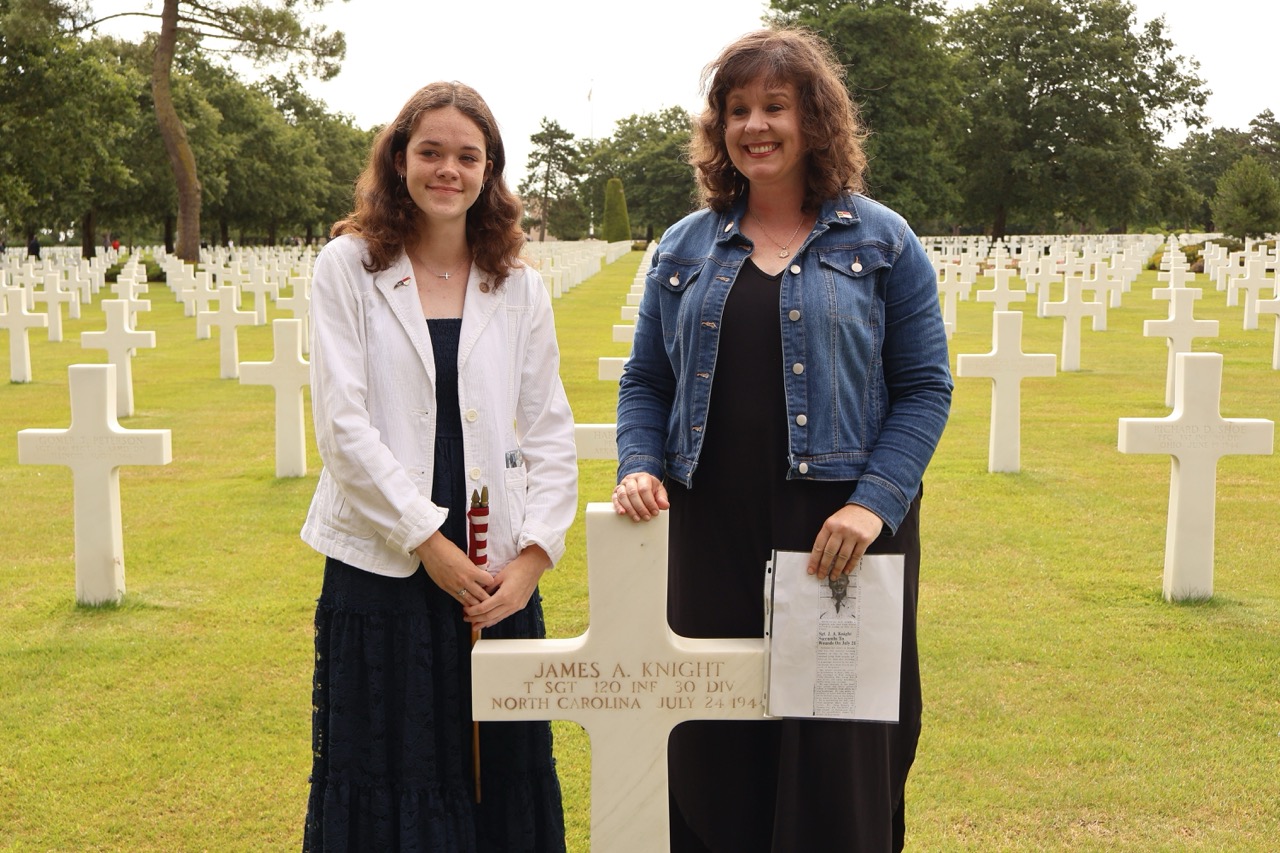 2024 participants standing at headstone in Normandy American Cemetery