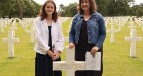 2024 participants standing at headstone in Normandy American Cemetery