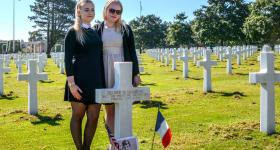 Two people standing with cross in Normandy American Cemetery